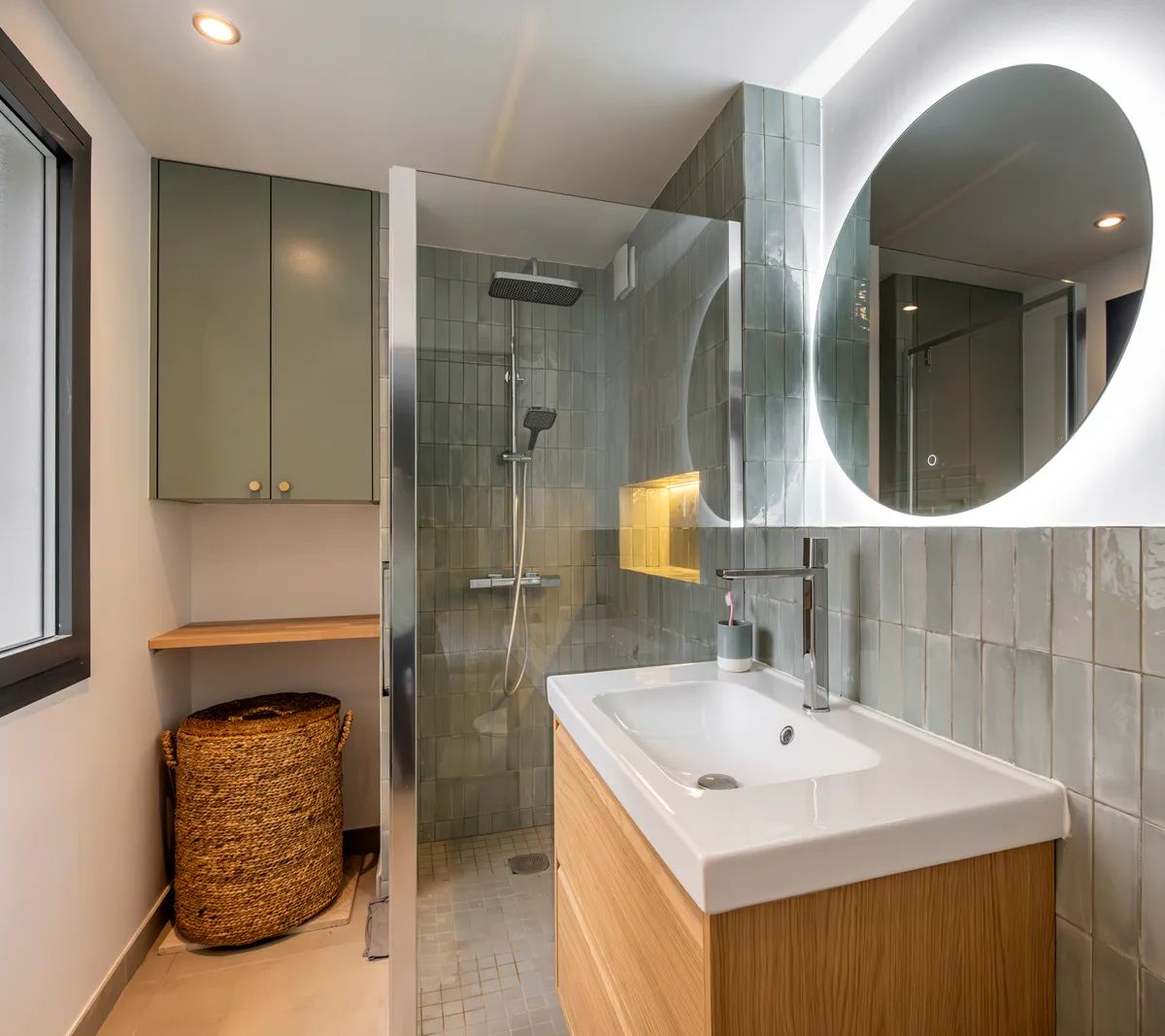 Salle de bain moderne avec douche à l'italienne, vasque bois, miroir rond et carrelage vert, design contemporain