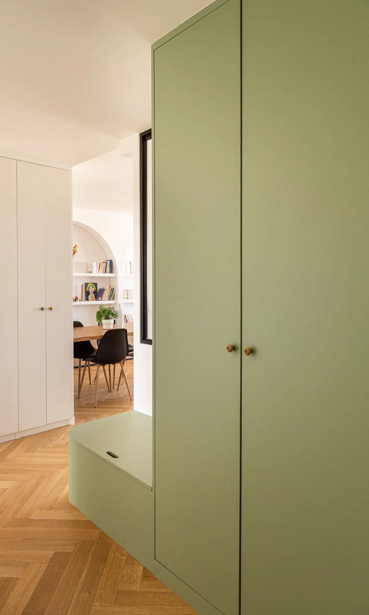 Placard de rangement vert olive avec banc intégré dans entrée moderne, parquet chevron, vue sur bureau