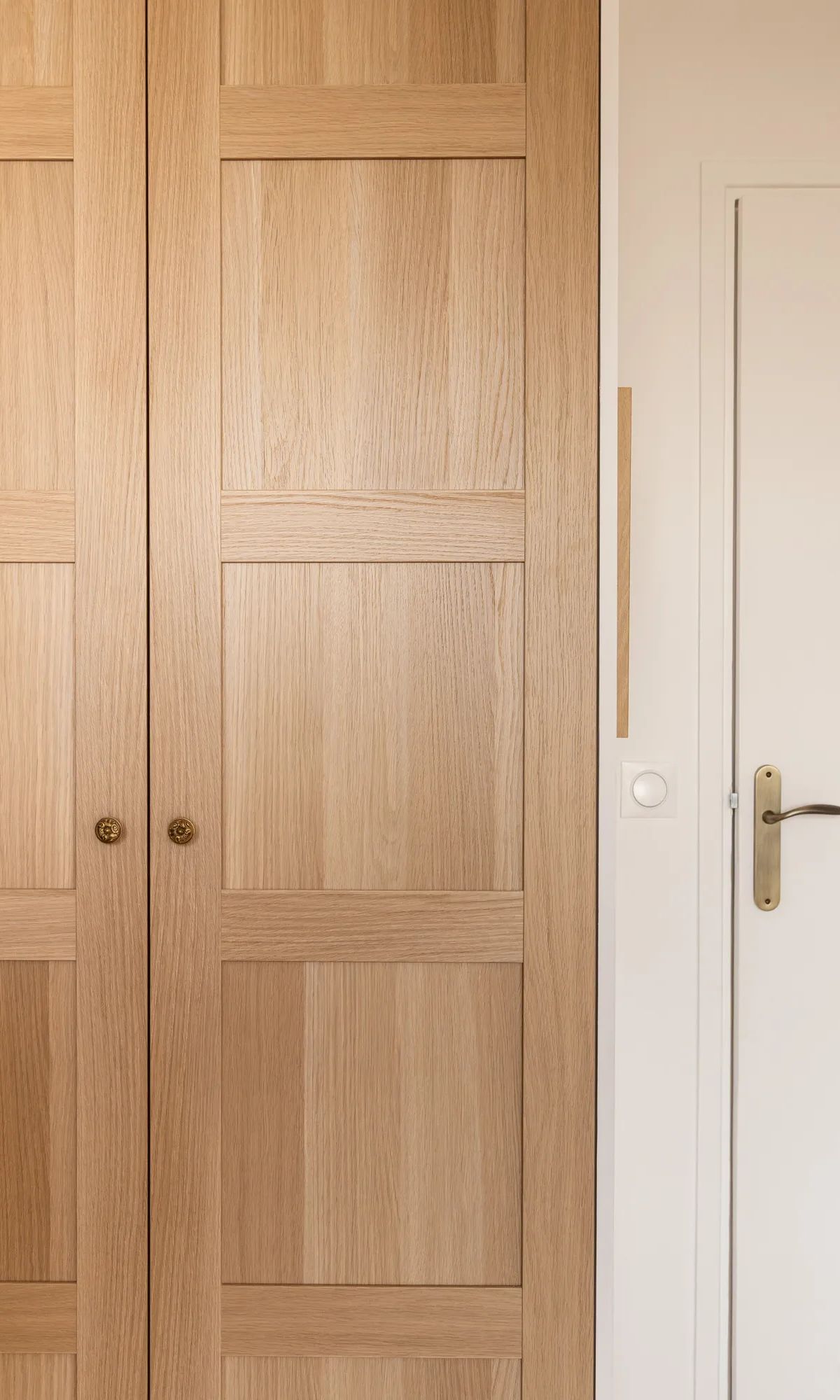 Portes coulissantes en bois clair style moderne avec poignées dorées et porte blanche à droite